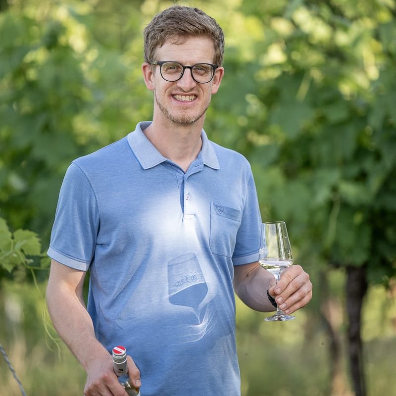 Porträt Winzer Herbert Steindl im Weingarten mit Weinflasche und Glas in den Händen - Weinbau Pröstler
